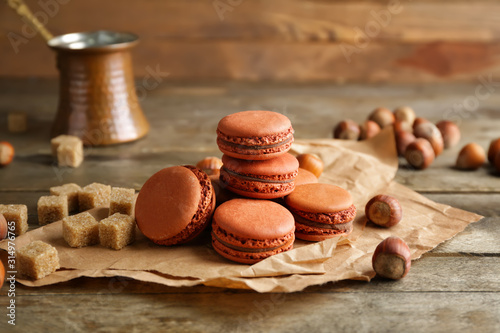 Tasty macarons with hazelnuts on table