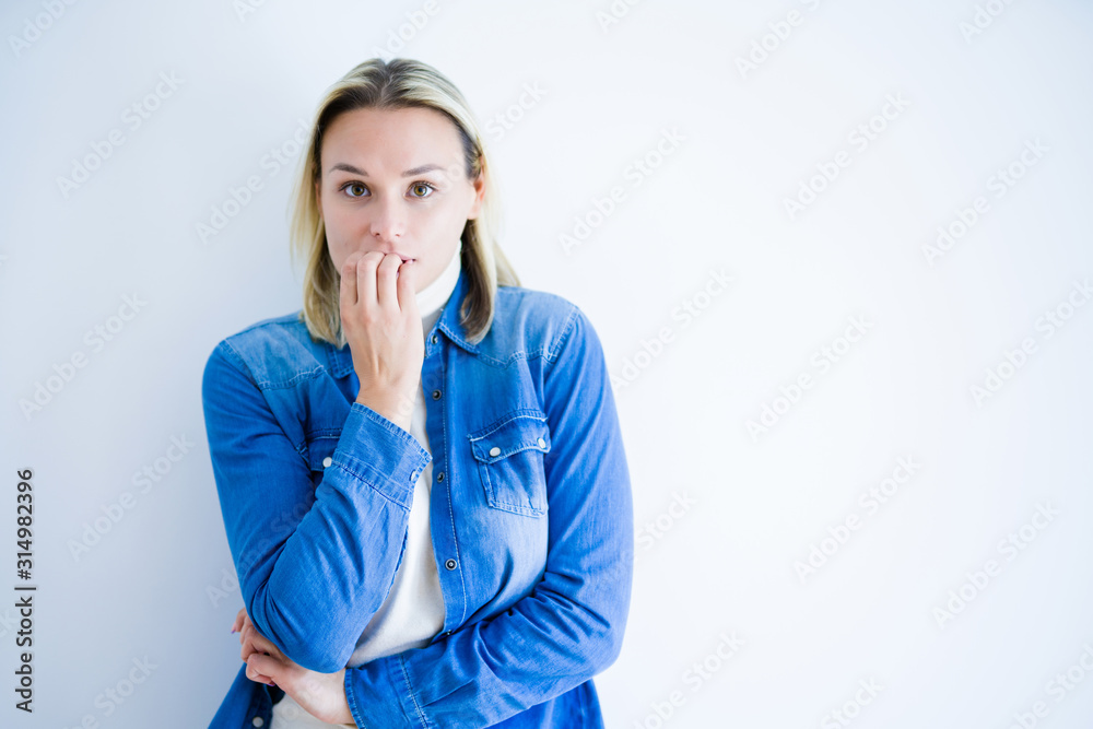Young beautiful woman wearing denim shirt standing over isolated white background looking stressed and nervous with hands on mouth biting nails. Anxiety problem.