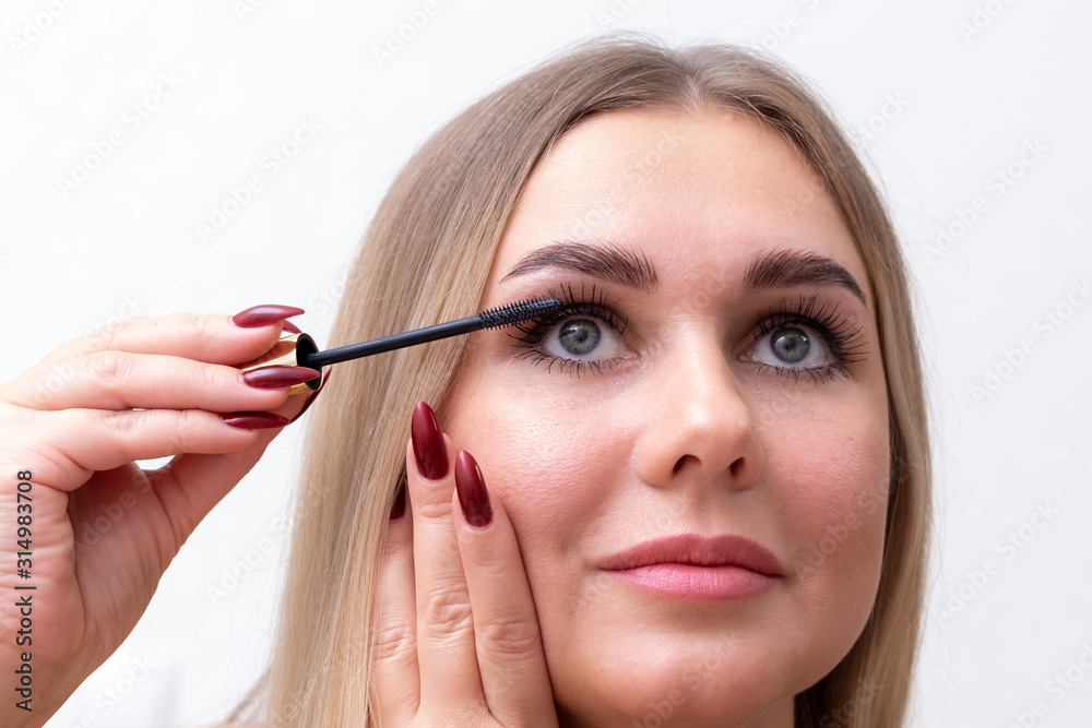 Beautiful blonde woman paints eyelashes. Beautiful female face. Makeup Read More Beauty girl with perfect skin. Makeup in progress