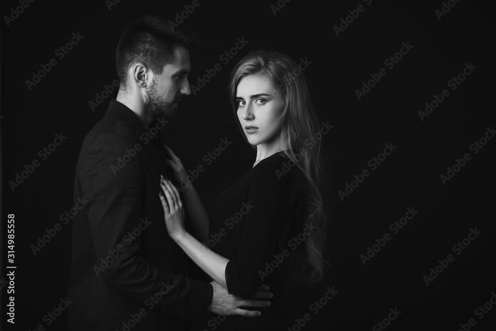 elegant couple in the tender passion. man embracing beautiful woman in black dress. black and white elegant couple in the tender passion. man embracing beautiful woman in black dress. black and white