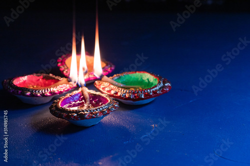 burning decorated ceramic oil lamp diya, on Happy Diwali, Shubh Diwali meaning with beautiful dark blue background, copy space