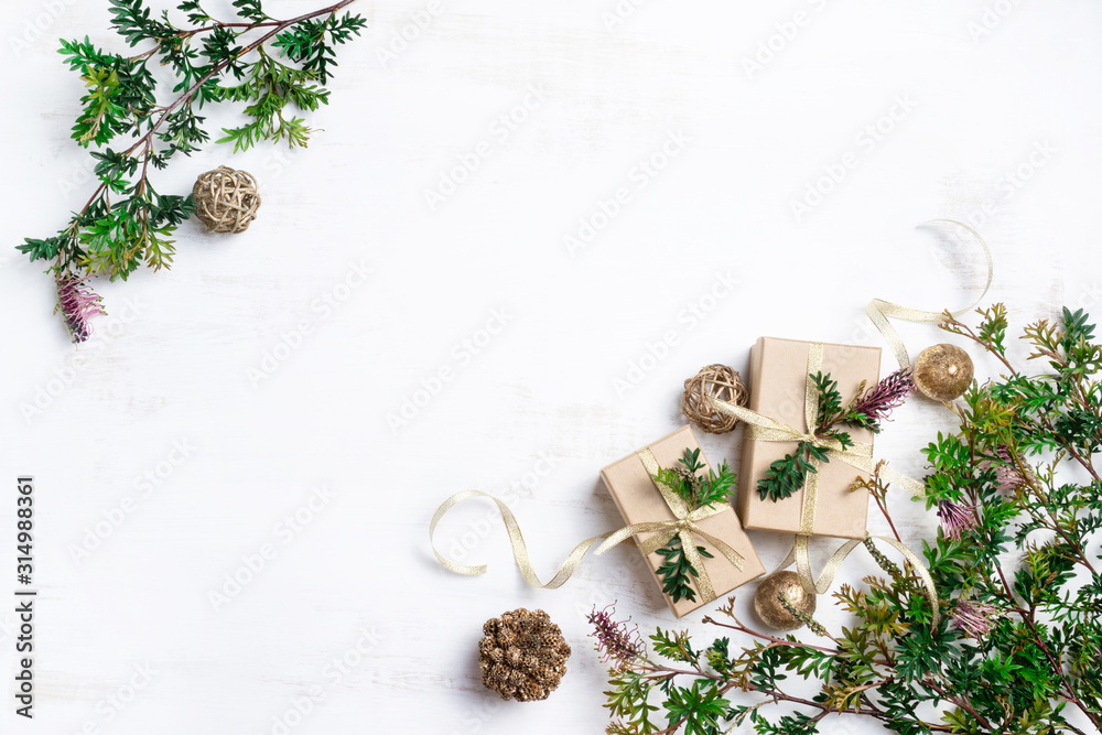 Australia native inspired Christmas background with gifts. Gold presents, ribbons and baubles surrounded by Australian native Christmas foliage Grevillea on a rustic white background.