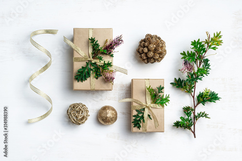 Australia Christmas background concept. Gifts, gold pine cones, Australian native plant Grevillea foliage and gold ribbon make up this natural flat-lay composition on a white background.