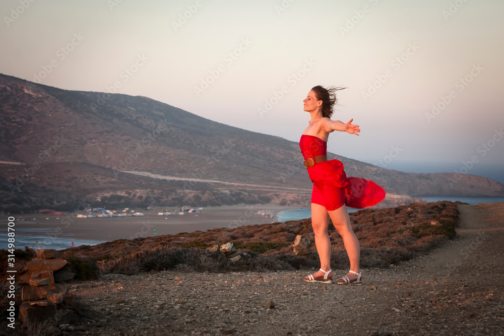 a girl in a red dress is picked up by a strong wind