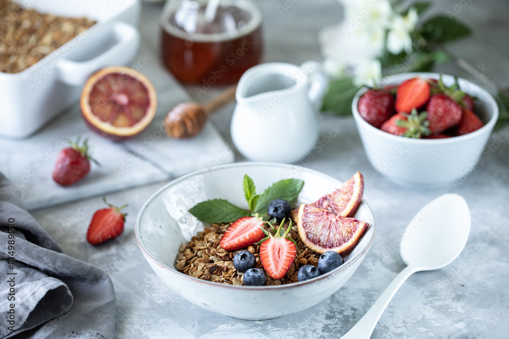 Healthy breakfast with granola, yogurt, fruits, berries on a white plate in white plate.