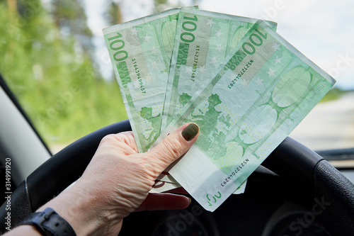 Euro banknotes in a woman hand inside of a car