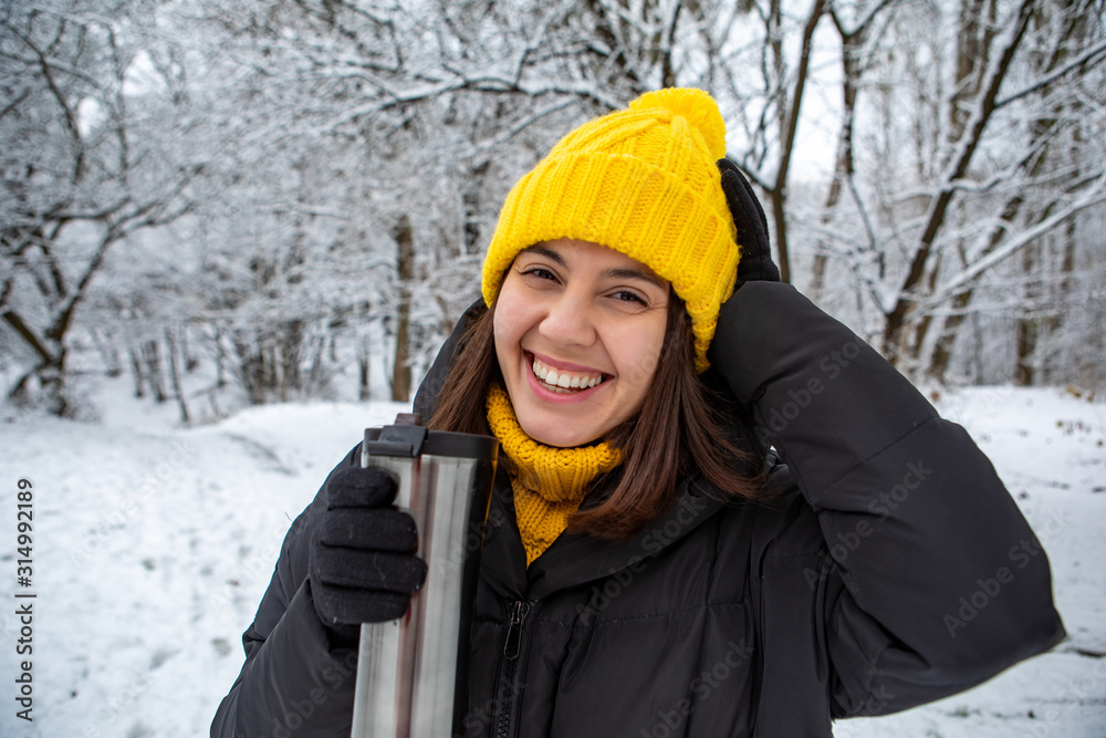 smiling woman in winter outfit drinking warm up drink from refillable mug smiling woman in winter outfit drinking warm up drink from refillable mug