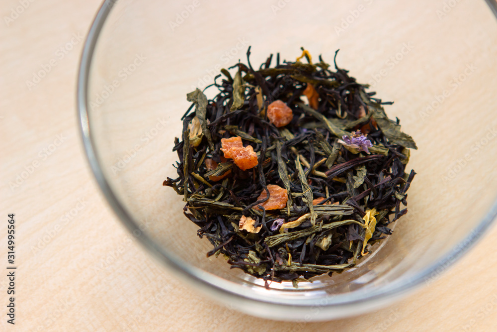 Fototapeta premium dry tea mix with herbs and fruit slices in a transparent cup, bowl, mug