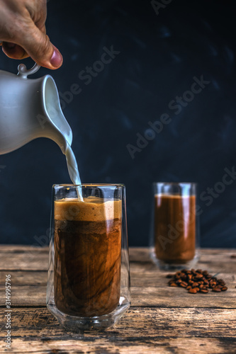 Cold coffee with ice and milk on a wooden table