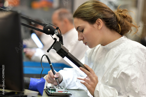 Fototapeta Young woman apprentice working in microelectronics lab