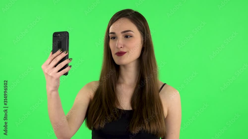 Smiling girl talking for video chat using mobile phone on green screen Smiling girl talking for video chat using mobile phone on green screen