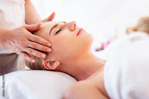 Beautiful young attractive Caucasian woman having head massage by Thai Masseur in spa salon. Beauty treatment and body care concept.