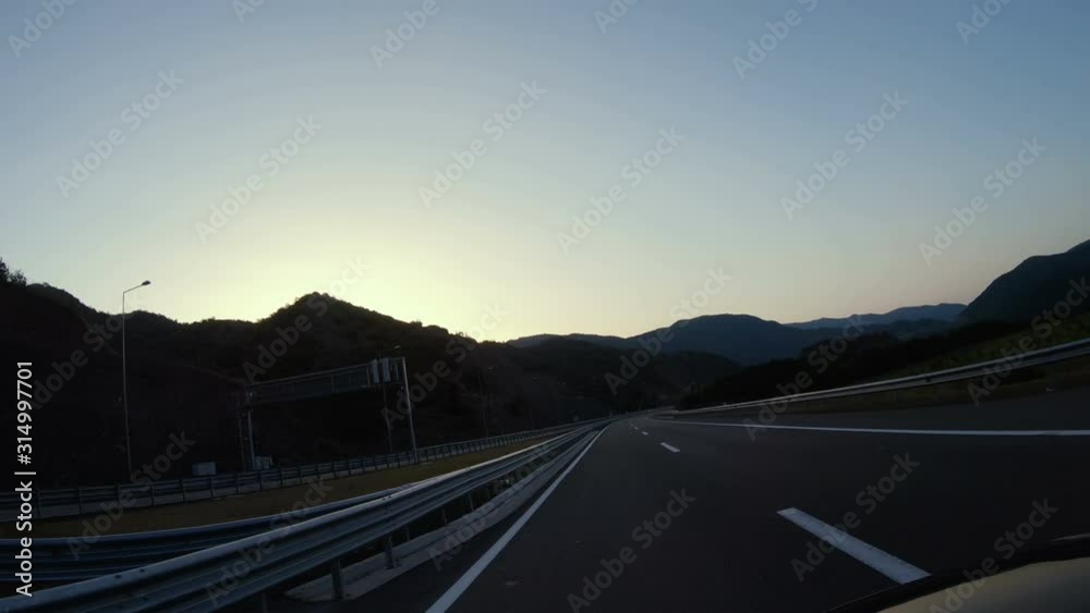 Driving pov at freeway tunnel and exit at sunset, sunrise sky