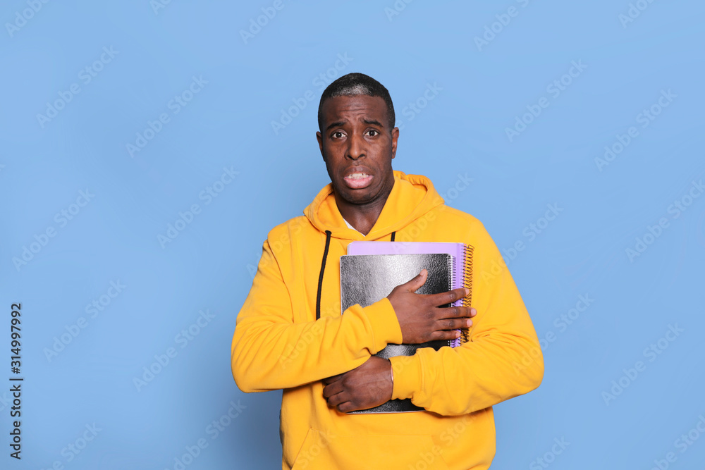 Horizontal shot of surprised scared black man stares at camera with popped eyes, standing against blue background Horizontal shot of surprised scared black man stares at camera with popped eyes, standing against blue background