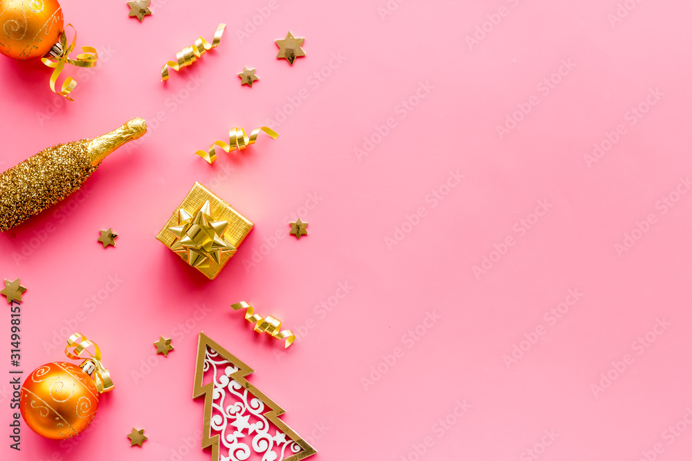 New Year symbols - tree, champagne, decorations - on pink background top-down frame copy space