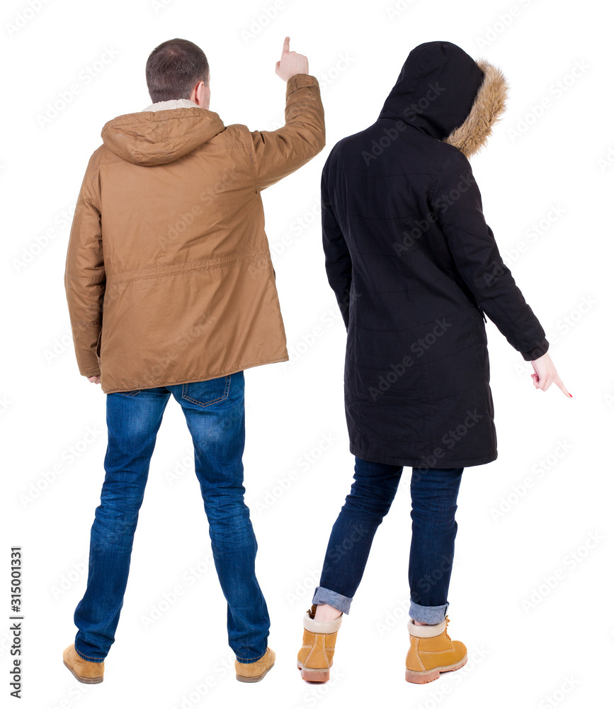Back view of couple couple in winter jackets pointing. Back view of couple couple in winter jackets pointing.
