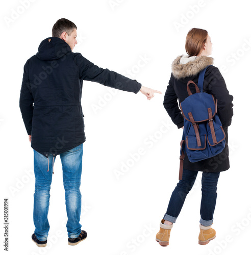 Back view of couple couple in winter jackets pointing.