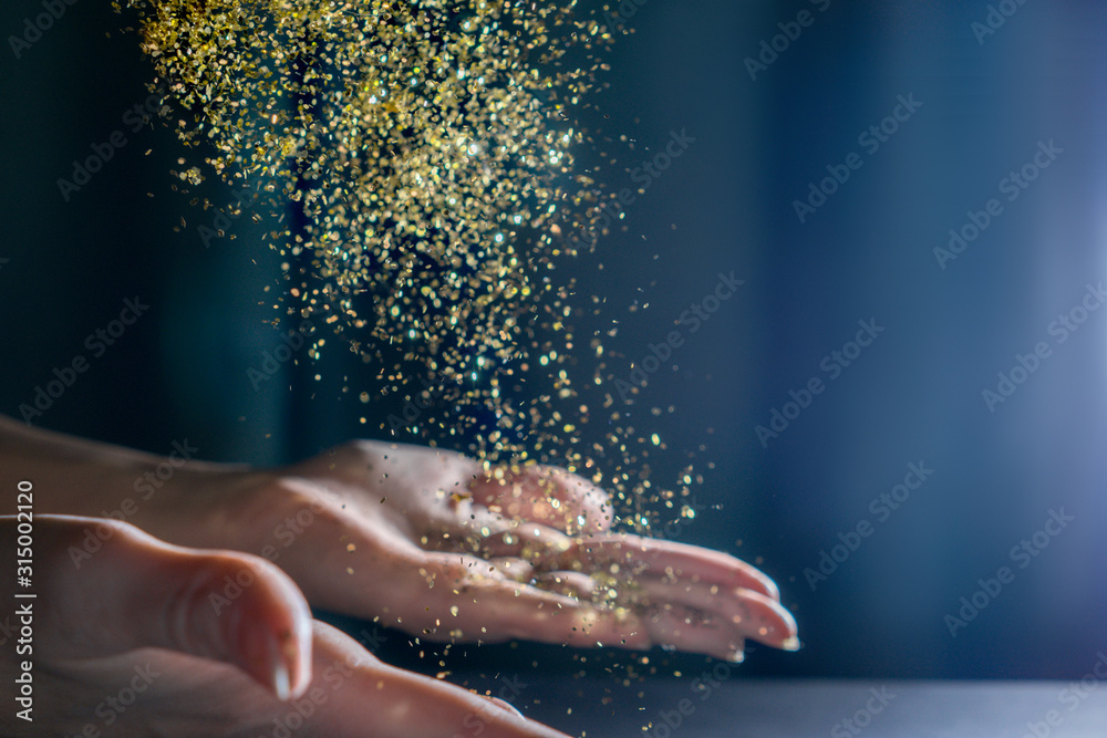 Hands with flying sequins. Light back.