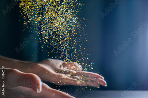 Hands with flying sequins. Light back.