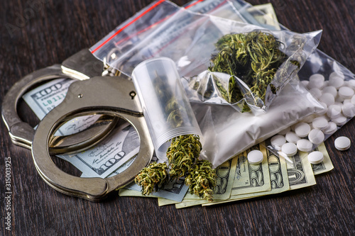 Fototapeta Naklejka Na Ścianę i Meble -  Cocaine in plastic bag and money on dark background, closeup.Cannabis herb and leaves for treatment.Buds. Skunk. cbd