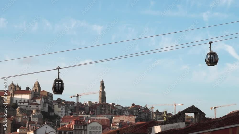 view of Gaia cable cars running in different directions, with Clerigos Tower in the background in old-town Porto view of Gaia cable cars running in different directions, with Clerigos Tower in the background in old-town Porto