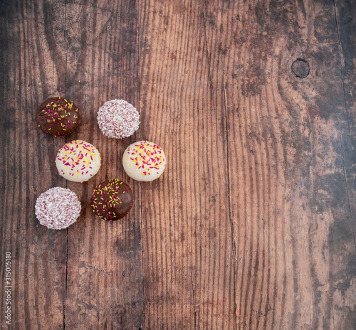Flat lay of six cupcakes arranged randomly on a wooden background with copy space