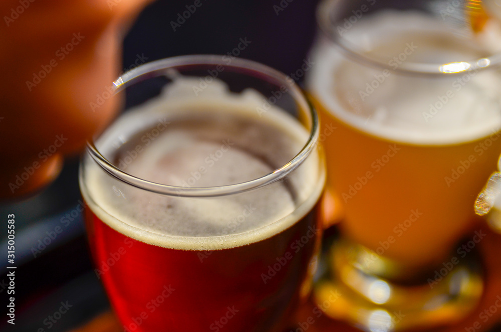 Craft beer tasting: an amber beer glass, next to a glass of blonde beer Craft beer tasting: an amber beer glass, next to a glass of blonde beer