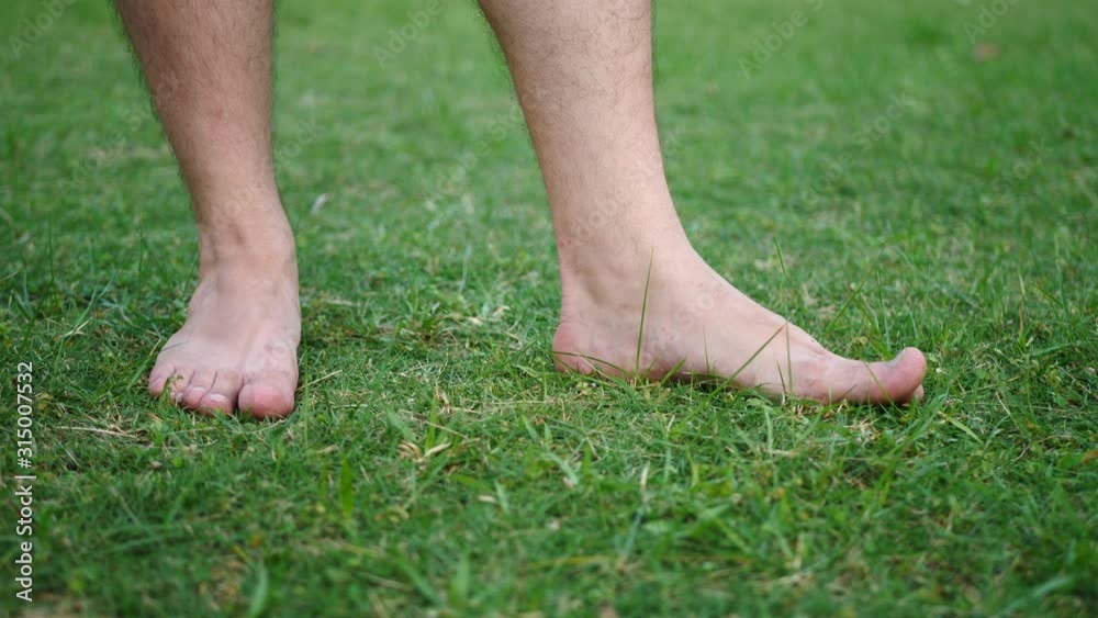 Barefooted Male Taps Toes On Fresh Cut Green Grass In Garden. Healchcare Concept Barefooted Male Taps Toes On Fresh Cut Green Grass In Garden. Healchcare Concept