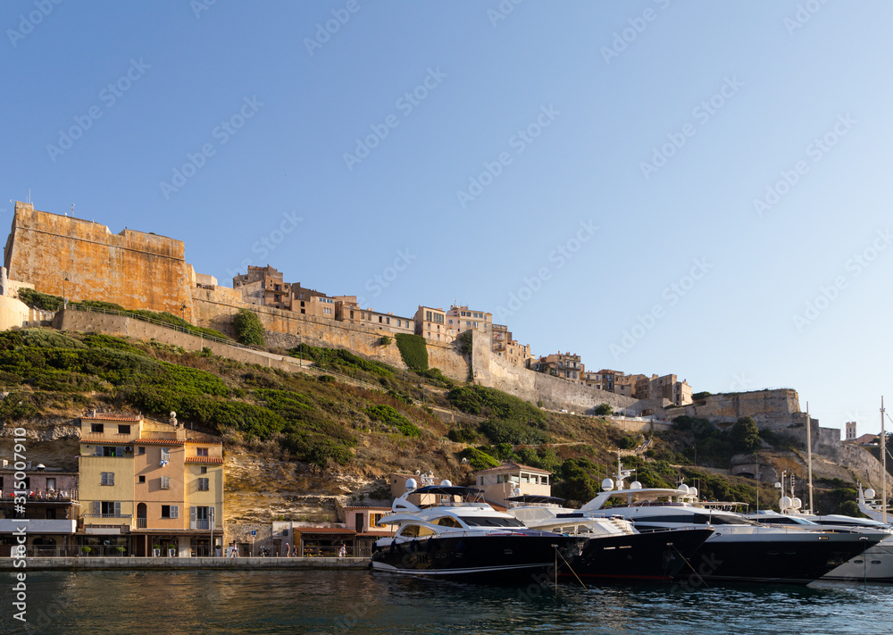 Luxury yachts anchored in front of the famous Bonifacio citadel in Corsica in France on a sunny summer day.