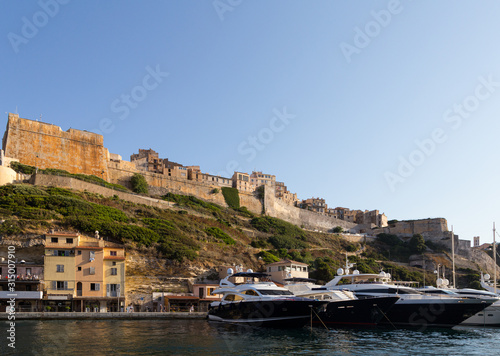 Luxury yachts anchored in front of the famous Bonifacio citadel in Corsica in France on a sunny summer day.