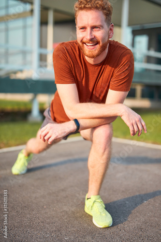 Young man exercising / stretching in urban park.