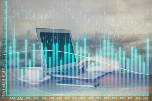 Double exposure of stock graph with businessman typing on computer in office on background. Concept of hard work. © peshkova