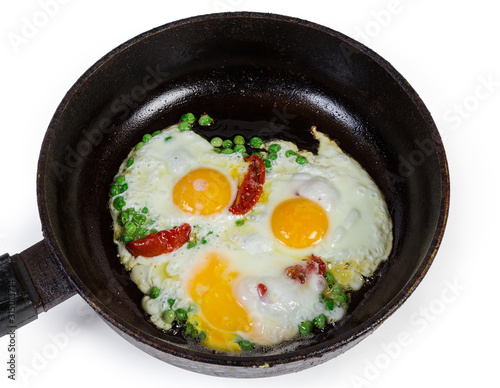 Eggs fried with green pea and tomatoes in frying pan