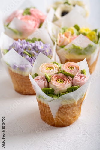 Flower cupcakes on white background. Beautiful sponge cup cakes decorated with buttercream roses. photo