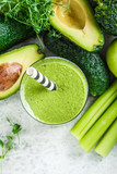 Green detox smoothie in a glass and ingredients for smoothie background, top view.