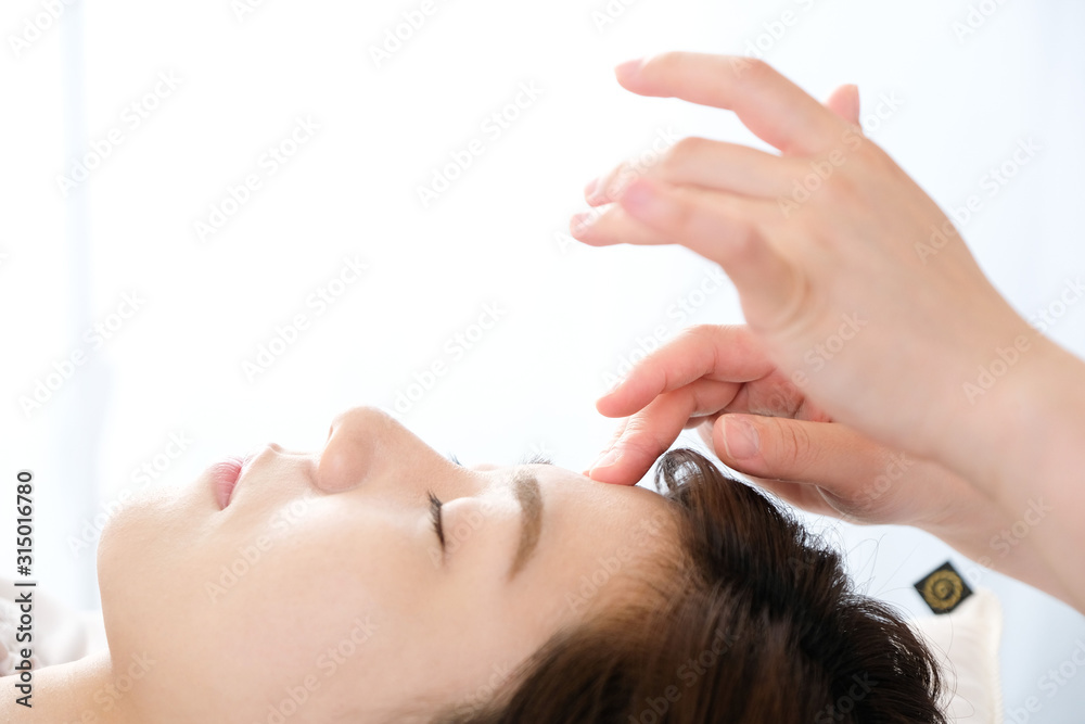 Fototapeta premium 鍼灸院で眉間の指圧を受ける女性