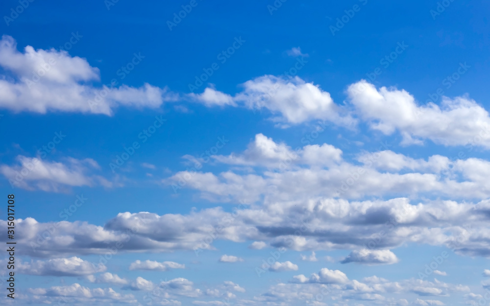 floating clouds in the sunlit blue sky