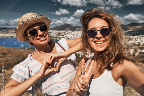 Two happy friends travelers making selfie photo on a hill in Bodrum at sunset light