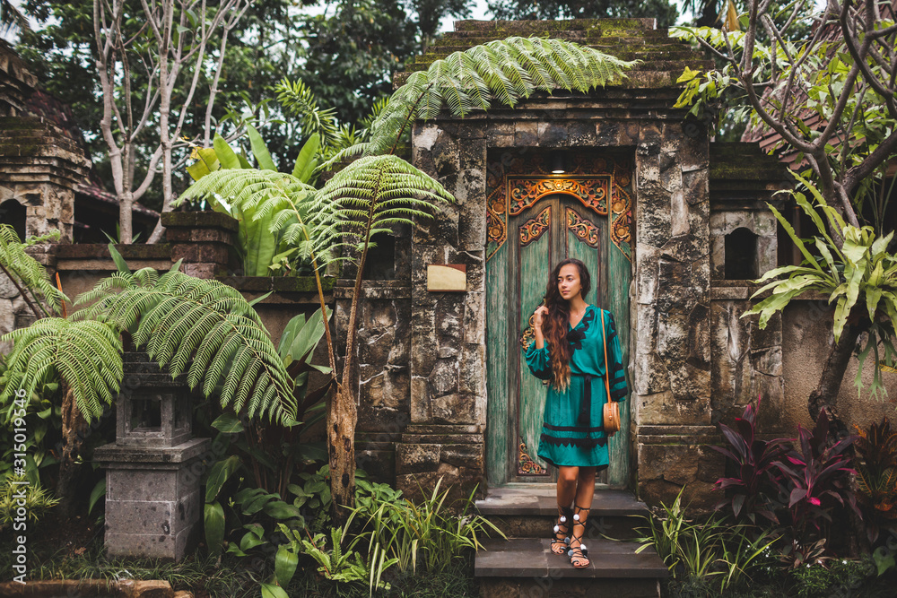 Asian brunette woman in ethnic green dress with handmade clutch