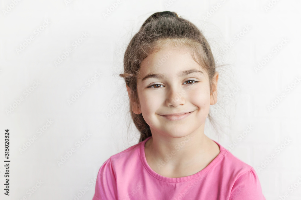 Portrait of happy laughing child girl on light background. Smiling kid. Positive emotions.