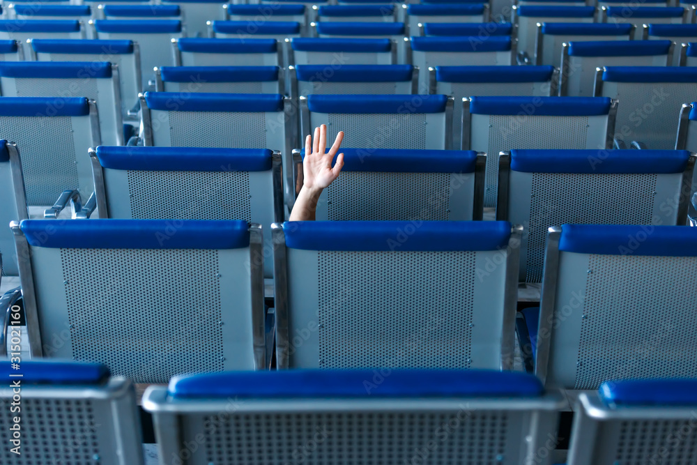 Naklejka premium Row of seats and a human hand in help gesture in airport hall