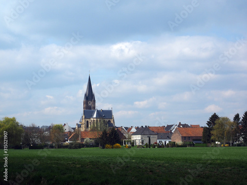View on the village Thorn with Onze Lieve Vrouwe Church and some houses in a agricultural landscape.