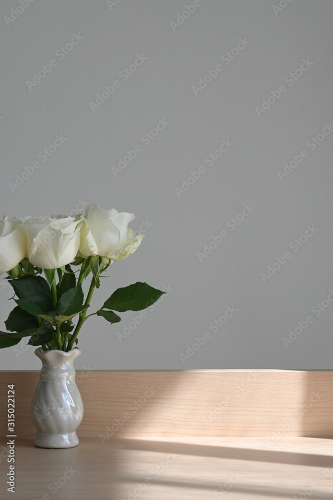 white rose blossom decoration in home, beautiful flower blooming in small vase put on wooden table with sunlight the morning day white rose blossom decoration in home, beautiful flower blooming in small vase put on wooden table with sunlight the morning day
