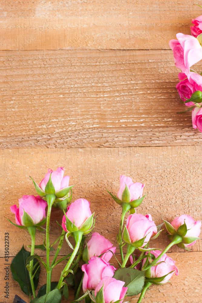 Small pink roses on a background of unpainted and untreated boards. Valentine's day composition, selective focus.
