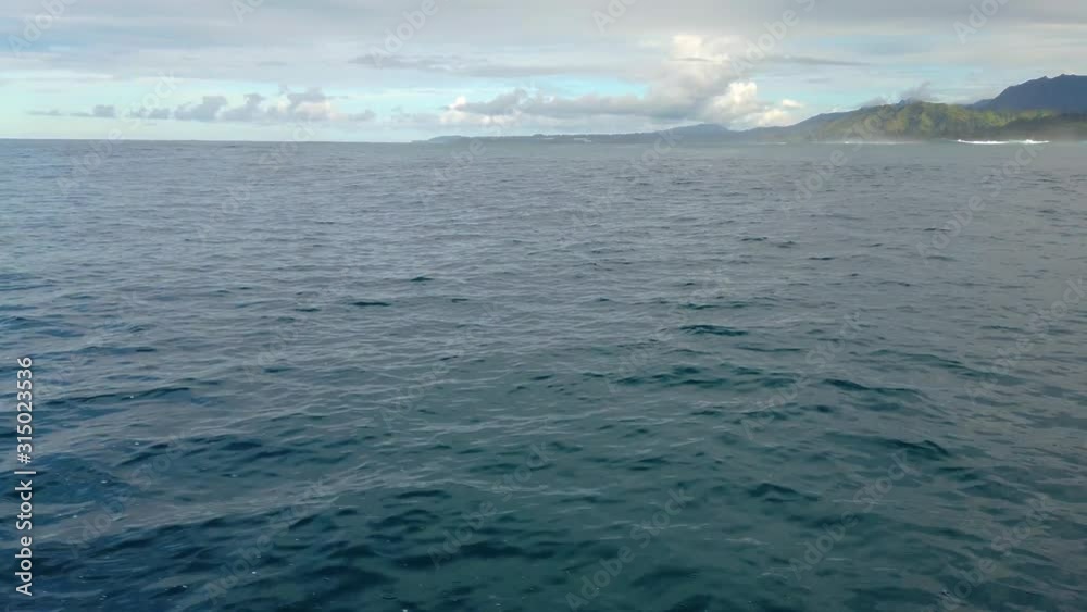 4K Hawaii Kauai Boating on ocean floating right to left tilted down to see cloudy shoreline in distance with boat spray in foreground 4K Hawaii Kauai Boating on ocean floating right to left tilted down to see cloudy shoreline in distance with boat spray in foreground