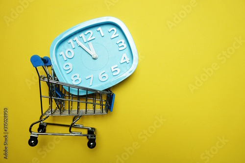 alarm clock and mini trolley cart with space copy on Yellow background photo