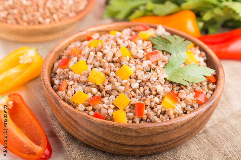 Buckwheat porridge with vegetables in wooden bowl on a white wooden background and linen textile. Side view, close up, selective focus, macro. Buckwheat porridge with vegetables in wooden bowl on a white wooden background and linen textile. Side view, close up, selective focus, macro.
