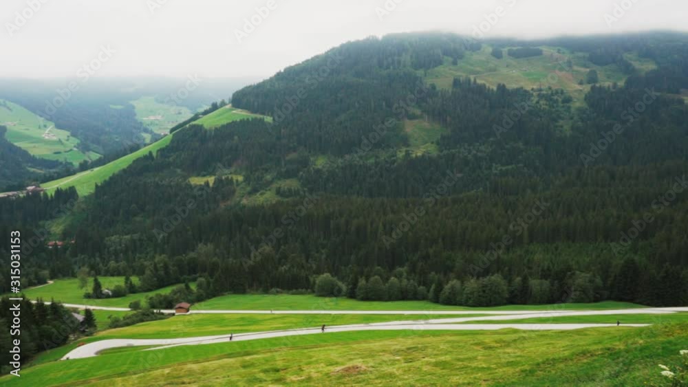 Panning right to left, showing the mountains in Auffach Austria, hikers moving along the road. Panning right to left, showing the mountains in Auffach Austria, hikers moving along the road.