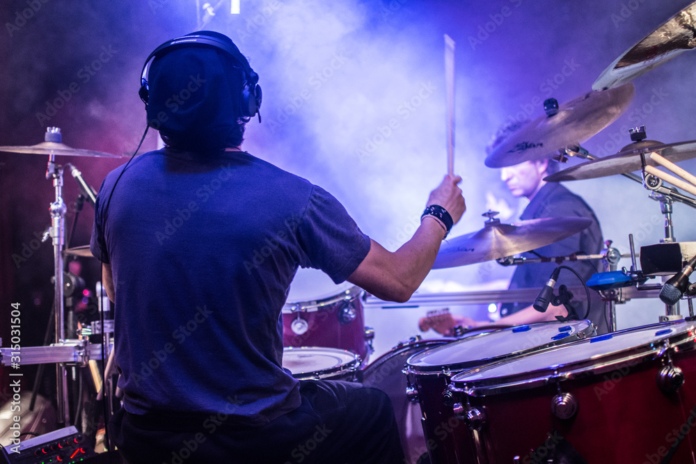 Φωτογραφία Batterista suona sul palco assolo di batteria durante il concerto, effetto fumo e luci