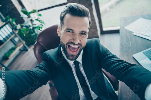 Closeyp photo of handsome business guy making taking funny selfies positive excited mood wear luxury black blazer shirt tie suit sit chair modern office indoors photo